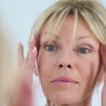 senior woman looking at her skin in mirror